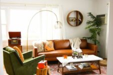 a stylish mid-century modern living room with a tan leather sofa, a green chair, a tiered coffee table and a stump and a floor lamp