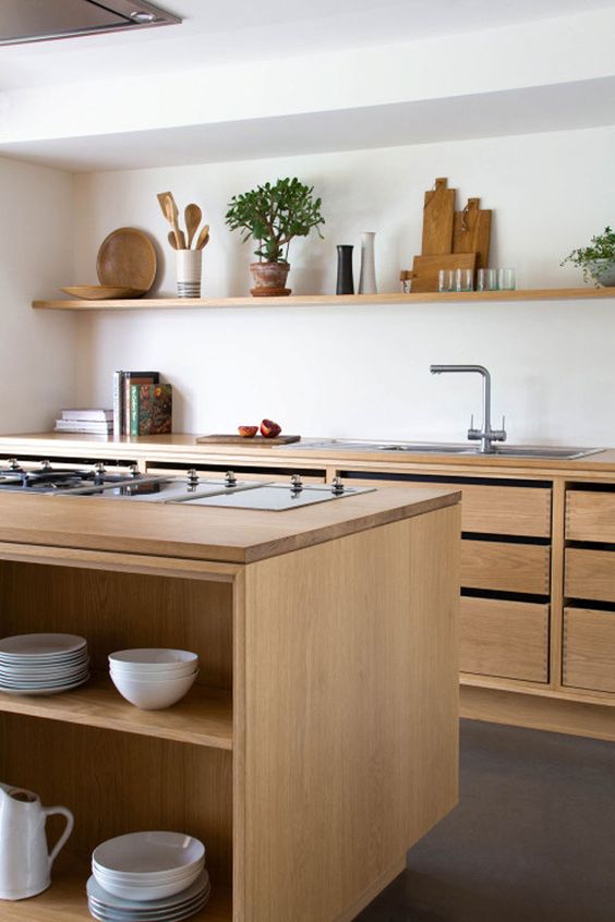 a stylish modern kitchen with stained cabinets and drawers, a large kitchen island, an open shelf for displaying and greenery