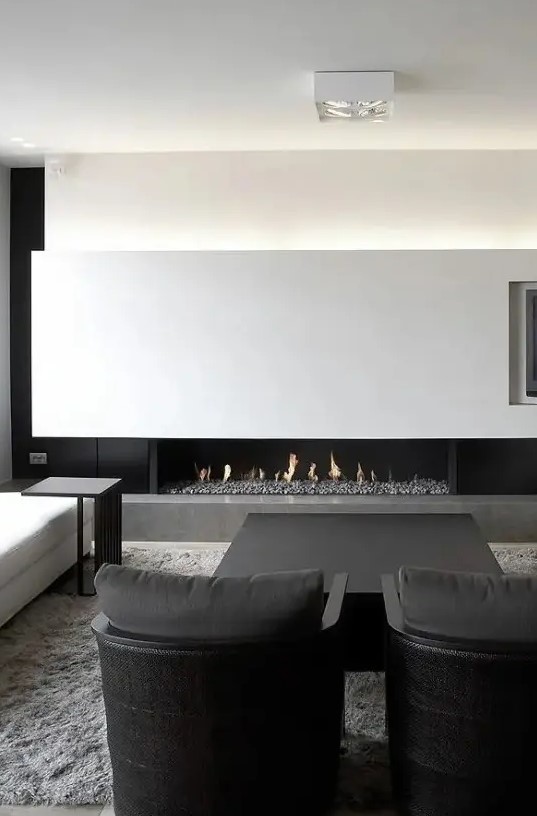a super elegant black and white minimalist living room with a lit up wall, a fireplace, comfortable black and white furniture