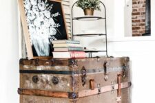 a vintage and shabby chic trunk as a console table in the corner, with books, a plant and an artwork is lovely