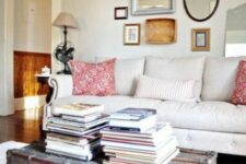 a vintage farmhouse living room with a neutral sofa, printed pillows, a vintage chest with books as a coffee table