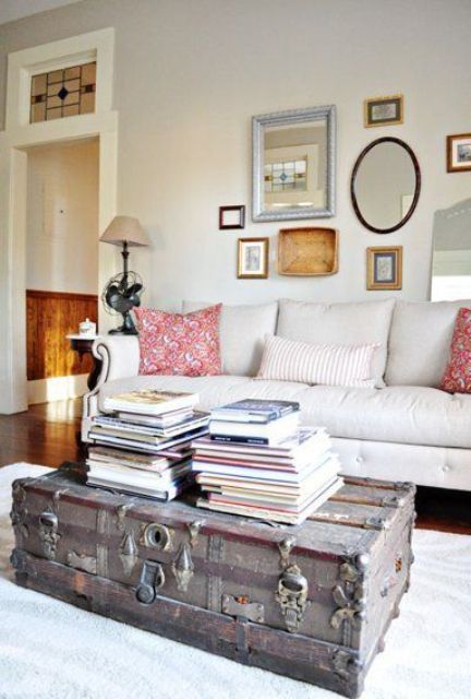 a vintage farmhouse living room with a neutral sofa, printed pillows, a vintage chest with books as a coffee table