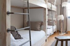 a wabi-sabi kids’ room with wooden bunk beds and metal ladders, floor lamps, a wooden stool and neural bedding