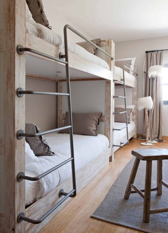 a wabi-sabi kids' room with wooden bunk beds and metal ladders, floor lamps, a wooden stool and neural bedding