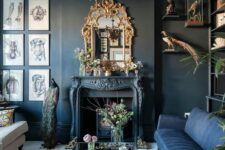 a whimsical living room with black walls, a vintage fireplace, a navy and a creamy sofa, an ornated frame mirror and a chandelier