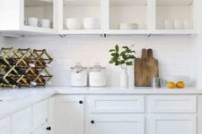 a white farmhouse kitchen with open upper cabinets, a white subway tile backsplash, stone countertops and a wine bottle stand