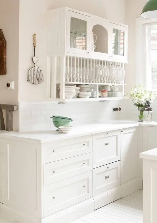 a white farmhouse kitchen with shaker and open cabinets that are used to display dishes and tableware