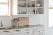 a white kitchen with open and shaker cabinets, neutral countertops and large scale tiles on the backsplash