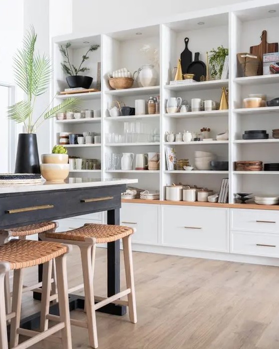 a whole wall taken by open cabinets that are used to display beautiful dishes, vases, cutting boards and other kitchen stuff