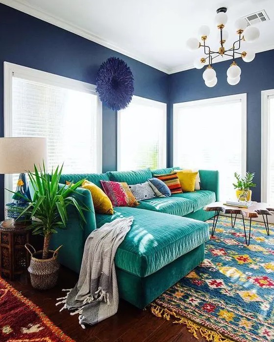 an L shaped emerald velvet sofa with colorful pillows is the main eye catcher that adds color to the space