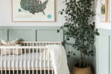 an airy and beautiful Scandinavian nursery with sage green paneling, a stained crub, neutral textiles, a potted plant and some art