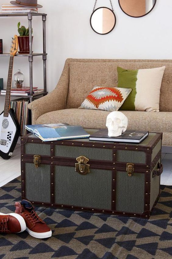 an eclectic space with a beige sofa and printed pillows, a printed rug and a vintage chest as a coffee table
