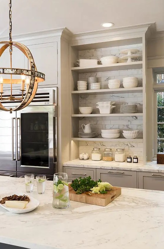 an elegant grey kitchen with shaker and open cabinets, white marble tiles and countertops and a cool sphere pendant lamp