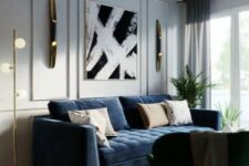 an elegant living room with dove grye walls, a navy sofa, a black chair, a chic artwork and some gold and brass touches for a chic look
