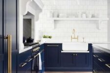 an elegant navy kitchen with shaker cabinets, white stone countertops, a large kitchen island, a white square tile backsplash and a white shelf for dishes