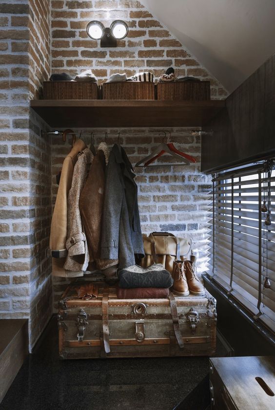 an industrial entryway with a vintage chest for storage and as a table, with a shelf with baskets and various stuff