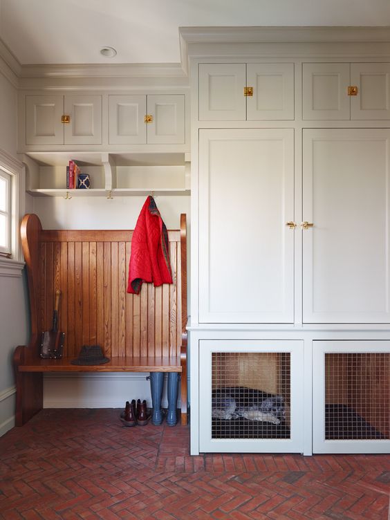 an off-white modern mudroom with shaker cabinets and a built-in dog crate in one of the lower cabinets