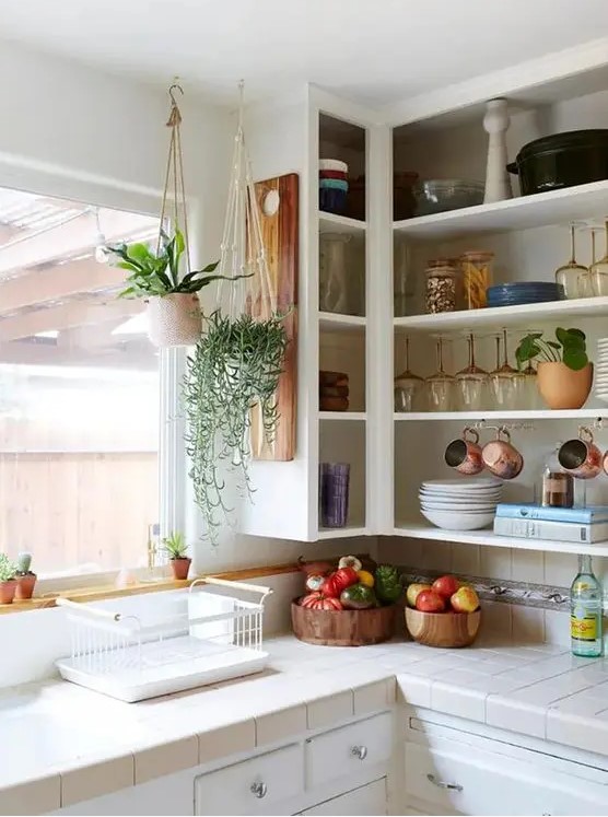 an open upper corner cabinet for displaying dishes, mugs, glasses, potted plants is a cool idea for a kitchen where there's enough storage space