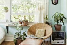 mint blue bedroom wiht a woven chair and a leather footrest, potted plants, a bed and a windowsill shelf plus a rug