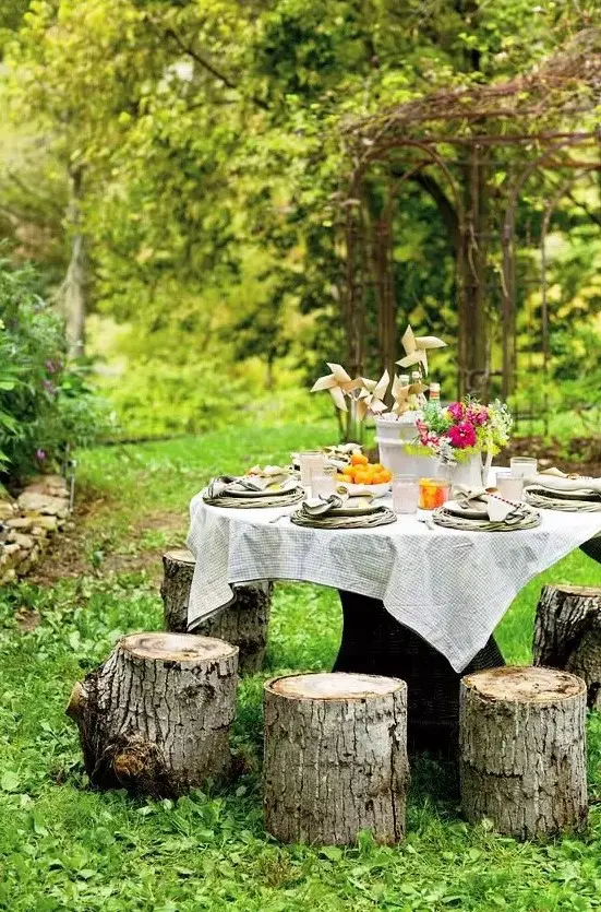 a beautiful garden dining space with a large table and simple tree stumps around it to sit on is a cool zone to have meals
