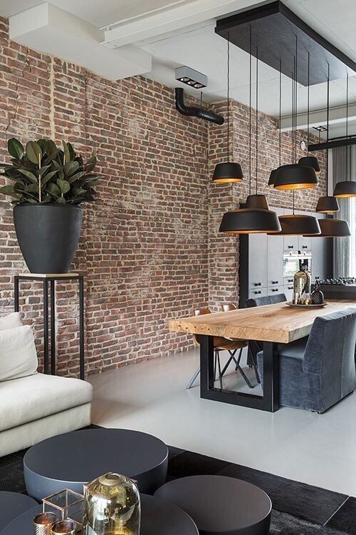 a stylish modern industrial space with a living edge table, grey chairs, a cluster of black pendant lamps and a potted plant