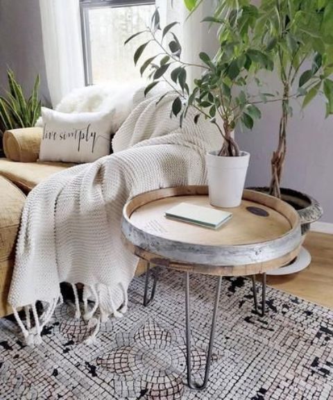 a cozy nook with a neutral chair and a an ottoman, a side table with hairpin legs, potted greenery and a printed rug