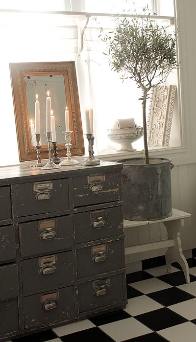 a shabby chic black apothecary cabinet with candles, a potted plant next to it is great decor for a vintage space