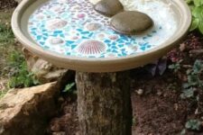 08 a tree stump holding a beautiful mosaic bird bath with seashells and pebbles is a lovely idea for any garden