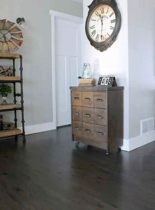 a small reclaimed wood apothecary cabinet placed on casters as a cute and eye-catchy entryway console