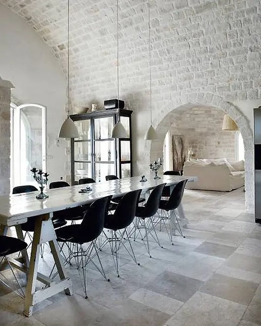 white brick going from the walls to the arched ceiling look bold with contemporary furniture in black creating an eclectic look