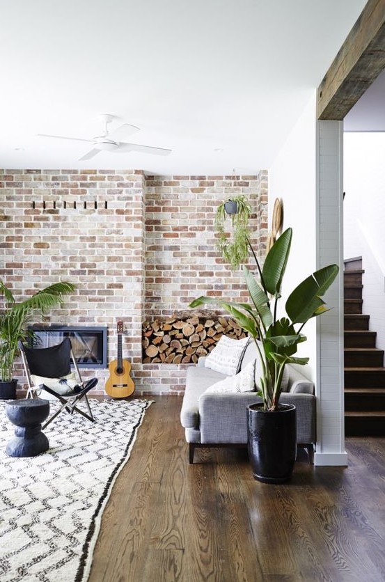 a boho living room with a whitewashed brick wall, potted greenery and neutral furniture
