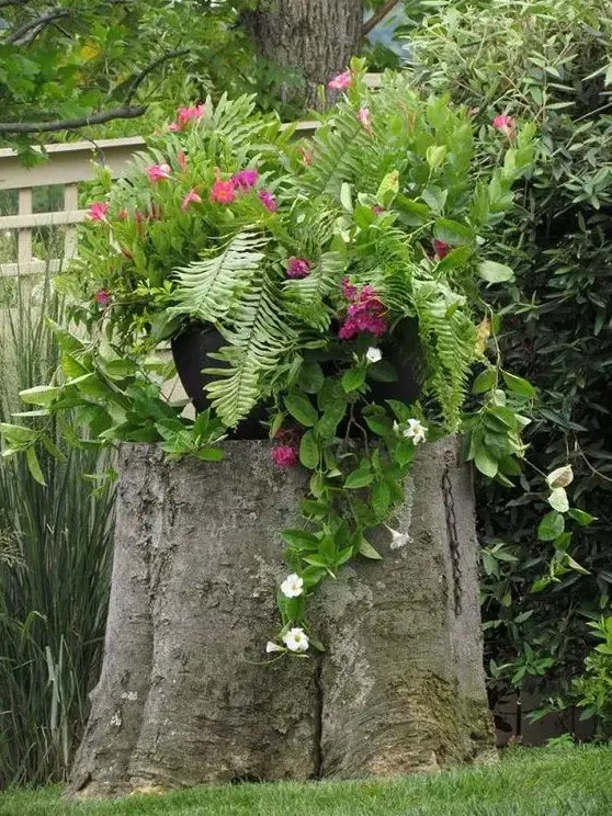 a large tree stump as a planter stand, a large pot with greenery and bright blooms are amazing for styling a garden