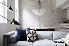 15 a contemporary living room with a whitewashed brick wall, chic furniture, a cluster chandelier and black for a touch of drama