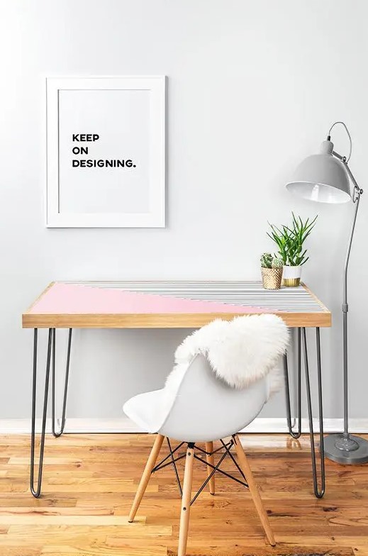 a pink and stripe color block desk with hairpin legs, a white chair, a grey floor lamp and an artwork for working