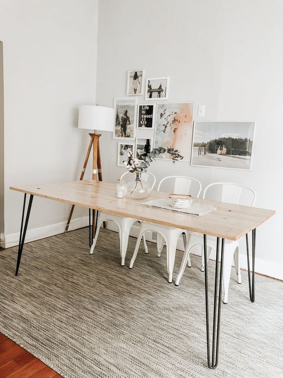 a Scandi dining room with a hairpin leg dining table, white metal chairs, a gallery wall and a floor lamp, a printed rug