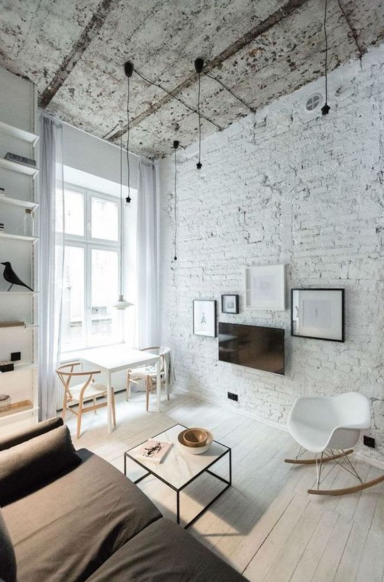 a monochromatic living room with a white brick wall and a rough ceiling for a touch of drama