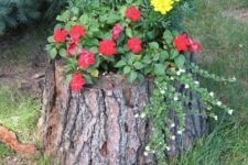 21 a tree stump with bold blooms and greenery and a butterfly on top is a stylish and catchy idea for a garden