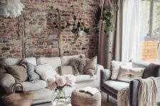 23 a neutral boho living room with a shabby chic brick accent wlal, neutral seating furniture, jute poufs, potted plants and a pendant lamp