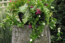 23 a tree stump with greenery and bright and white blooms is a catchy decoration for a garden