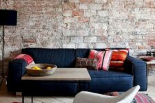 27 a rough brick wall with bricks of various sizes and colorfuul furniture and rugs to contrast