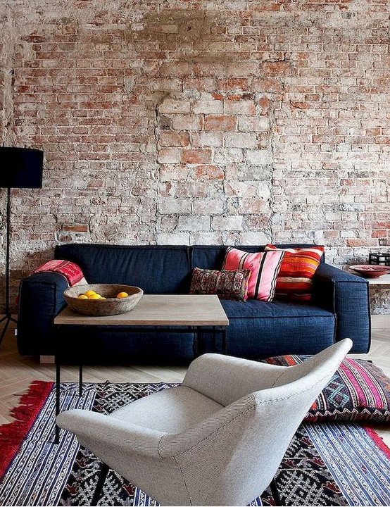 a rough brick wall with bricks of various sizes and colorfuul furniture and rugs to contrast