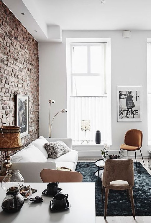 the exposed brick wall gives the living room a lot of character already, which is enhanced by the contrasting black and white