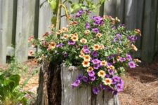 33 an old stump with yellow and purple blooms and greenery is a very eye-catchy decoration due to the contrast