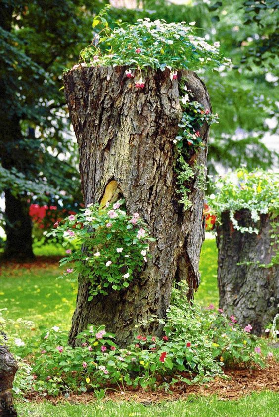 tree stumps with greenery and bright blooms plus greenery and blooms around are a catchy and super natural decoration for any garden
