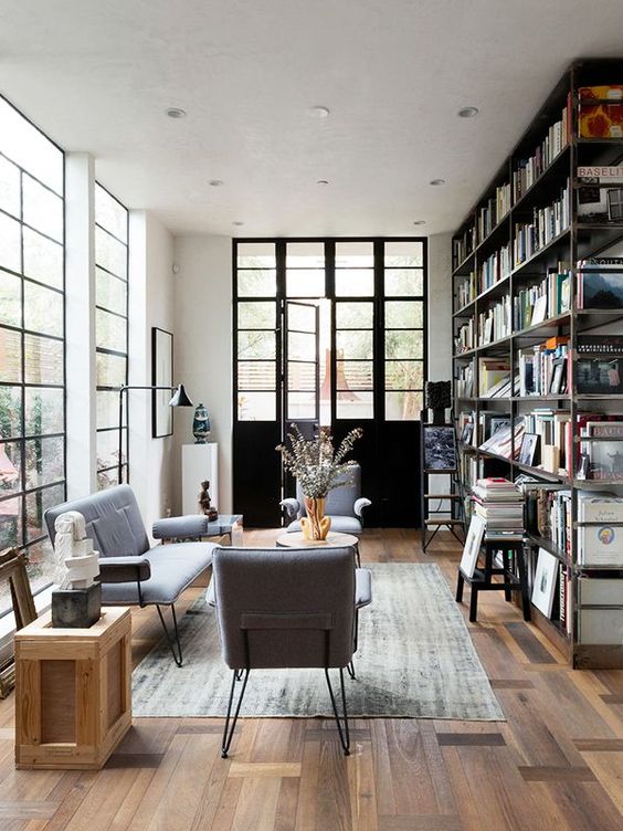 a stylish living room with a large bookcase, grey hairpin leg furniture, a crate and a coffee table, a grey rug is cool