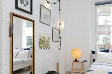 39 a dreamy Scandinavian bedroom with a white brick wall, a whitewashed floor shows off black framed art and dark bedding