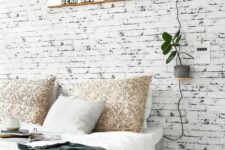 41 a Nordic bedroom with a whitewashed brick wall, a grey bed, lights and plants is a stylish and welcoming space