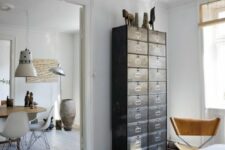 43 a light-filled Scandinavian space with a dark card cabinet that is used instead of a usual dresser and a leather chair