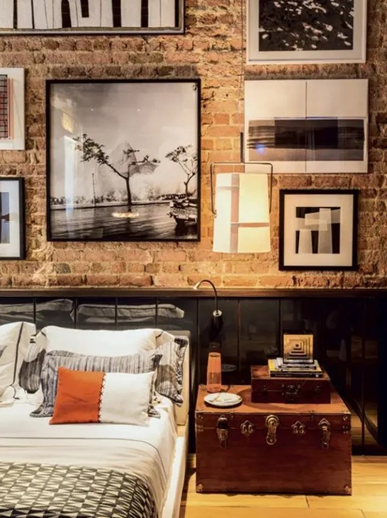 a vintage industrial bedroom with a brick wall and sleek black panels, vintage furniture and a gallery wall