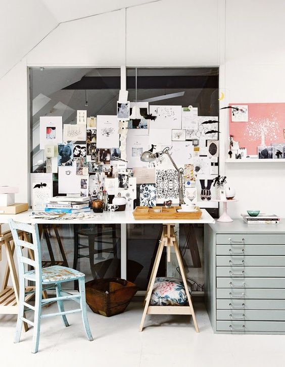 a working space with a trestle desk, a blue chair and a blue file cabinet for storage, a memo board and a table lamp